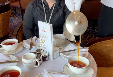 A white-gloved steward pours the tea on QM2